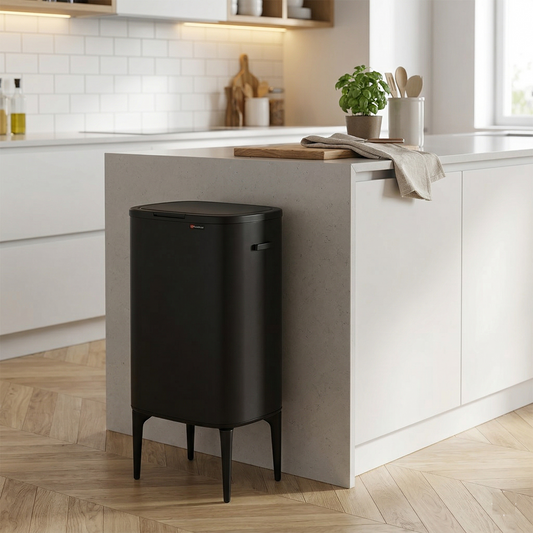 פח Calabria שחור על רגליים עומד בגובה אידיאלי למניעת התכופפות במטבח מעוצב עם רצפת פרקט ואי מטבח עם שיש בהיר.